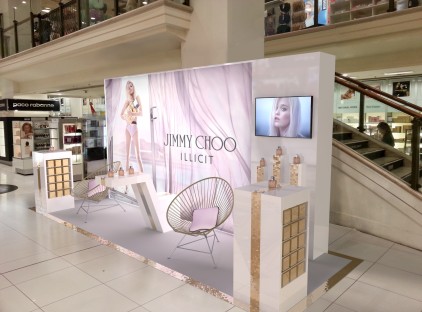 display stand with large graphic, chairs, tv and perfume bottles