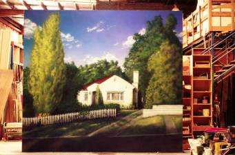 Large painted canvas of house and trees inside a workshop